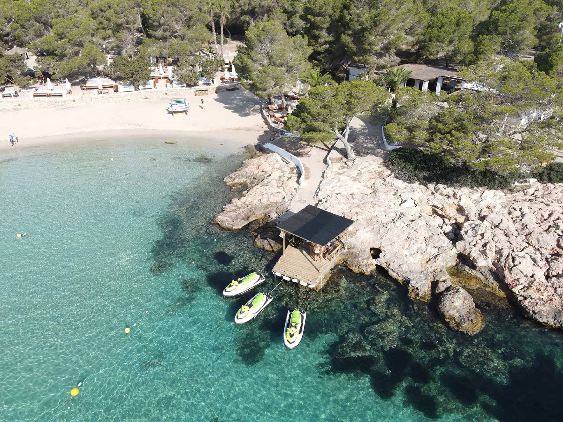 Vista aerea di tre moto d’acqua ormeggiate in una cala turchese di Ibiza